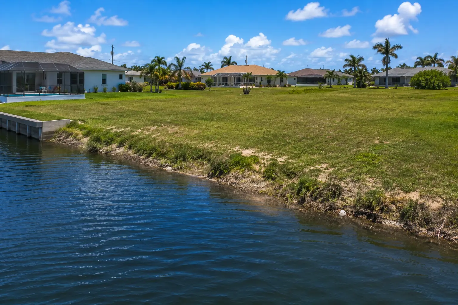 Cape Coral waterfront lot with existing seawall compared with vacant canal lot needing seawall construction